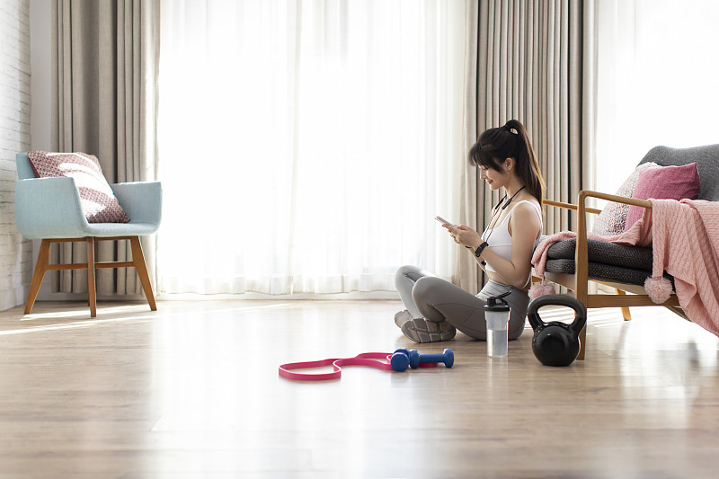 年轻女子运动后玩手机图片下载